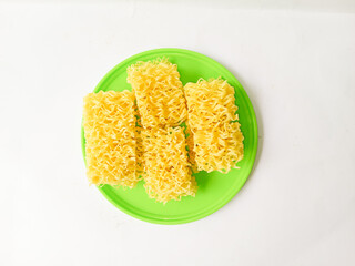 Raw dry yellow noodles served with green plate isolated on white background