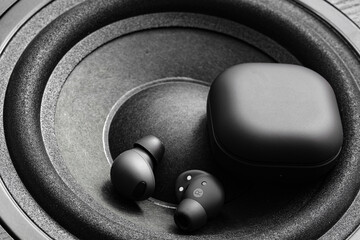 black wireless earpone buds on speakers background