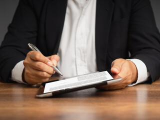 Businesswoman signing a digital contract or agreement on a tablet while sitting in the office