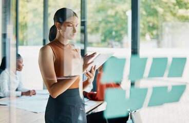 Things get done in this boardroom. Cropped shot of an attractive young businesswoman using her tablet while standing in the boardroom.