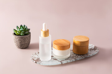 Fototapeta na wymiar Natural cosmetics in frosted glass bottles and a jar with a bamboo lid on a white tray. pastel background. A copy of the space.