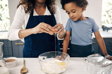 Closeup of female hands cracking a egg into a bowl while baking at home with her son. Woman adding...