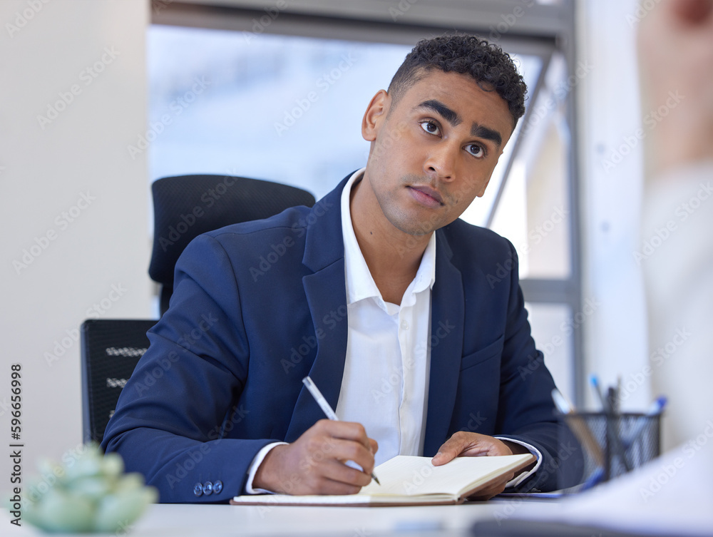 Poster taking note of all feasible ideas. shot of a young businessman writing notes while working in an off