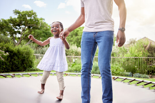 Ill hold you hand so you can jump high. Shot of a little girl jumping on a trampoline with her father outdoors.