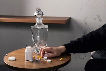 a hand reaches to a table and grabs pile of pills and medicine.