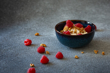 Bowl with greek yoghurt, granola and berries on dark grey background