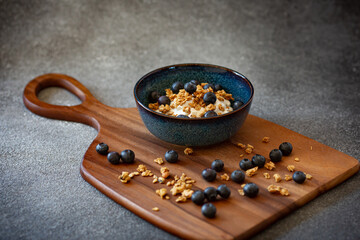 Bowl with greek yoghurt, granola and berries on dark grey background