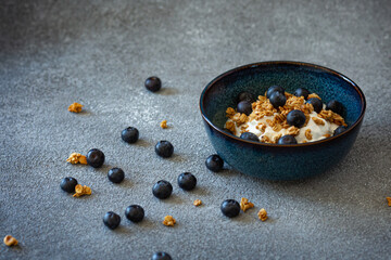 Bowl with greek yoghurt, granola and berries on dark grey background
