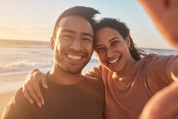 Portrait of a young diverse biracial couple taking a selfie at the beach and having fun outside. Portrait of a young diverse biracial couple taking a selfie at the beach and having fun outside. - Powered by Adobe