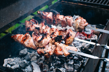 Frying meat pork on the grill. Shish kebab for summer party. Shashlik on wooden panels and open fire.