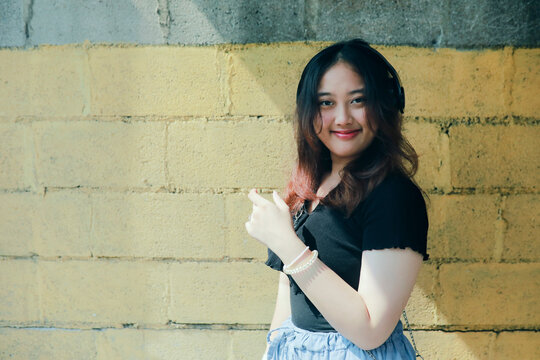 Asain Younger Woman Standing Among Sun Light And Shade Of Building Smiling With Relaxing Face