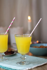 Plate of chocolate pralines, bowl of cookies, cups of tea, glasses of juice and lit candles on the table. Selective focus.