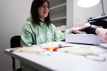 Manicure master working with female client in beauty salon. Manicurist makes woman nail.