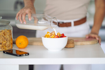 Woman preparing healthy meal with fruits and milk