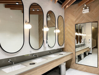 Minimal style and modern beautiful interior design of public restroom with row of mirrors, sinks...