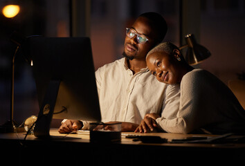 The romance is brewing between them. Shot of two affectionate businesspeople working together on a computer in an office at night.