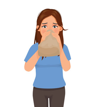 Young woman having panic attack breathing into paper bag 