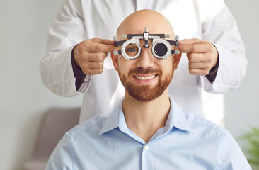 Optometrist specialist with ophthalmic phoropter optometer ocular device tool measures astigmatism...