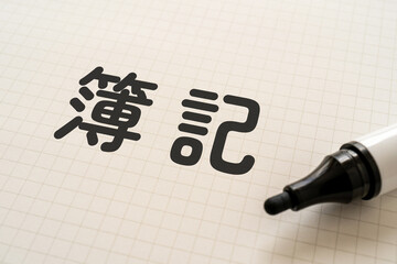 簿記と書かれたノートとマーカー