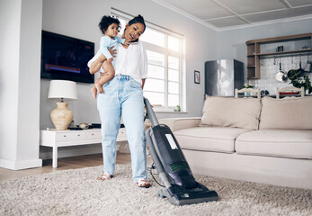 She does it all. Shot of a young mother using a cellphone while completing housework and holding...