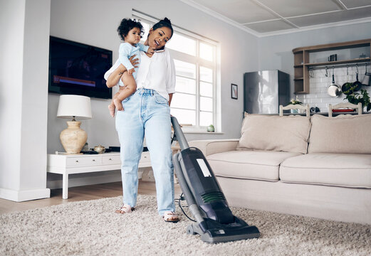 She does it all. Shot of a young mother using a cellphone while completing housework and holding her baby at home.
