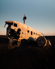 Man standing on Solheimasandur Plane Wreck on Iceland Black Sand Beach. High quality photo. Famous plane crash.