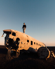 Man standing on Solheimasandur Plane Wreck on Iceland Black Sand Beach. High quality photo. Famous plane crash.