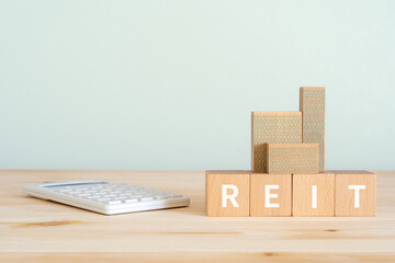REITと書かれたブロックと電卓と建物のオブジェ