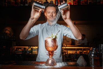 male bartender prepares a cocktail and sprinkles with powder