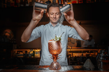 male bartender prepares a cocktail and sprinkles with powder