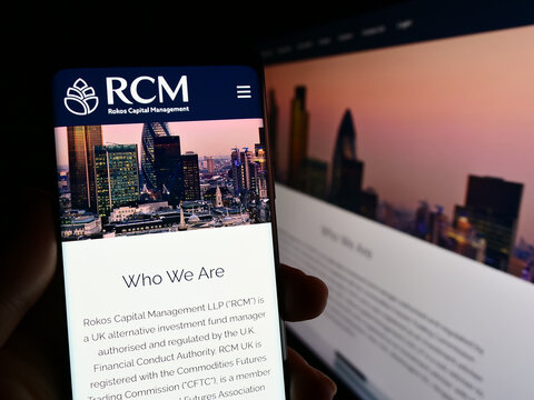 Stuttgart, Germany - 04-24-2023: Person holding smartphone with website and logo of company Rokos Capital Management LLP (RCM) on screen. Focus on center of phone display.