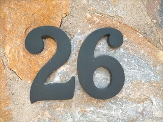 26, twenty-six in black metal number on natural stone surface