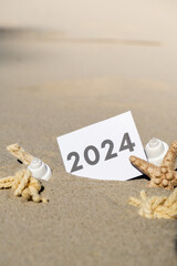2024 text start new year symbol on paper greeting card on background of starfish summer vacation decor. Sandy beach sun coast. Holiday concept postcard. Getting away Travel Business concept