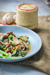 Sliced grilled beef salad, Isaan food in Thailand, local food in Thailand. Served with long beans and lettuce On a gray plate served in a Thai restaurant.