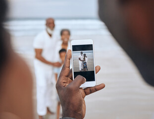 Great quality pictures. Cropped shot of an unrecognizable man taking a picture of a mature couple and their grandson at the beach.