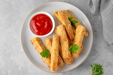 Baked crispy garlic parmesan zucchini sticks served with tomatoes sauce on a gray concrete background. Vegetarian healthy dish. Selective focus.