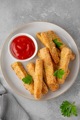 Baked crispy garlic parmesan zucchini sticks served with tomatoes sauce on a gray concrete background. Vegetarian healthy dish. Selective focus.