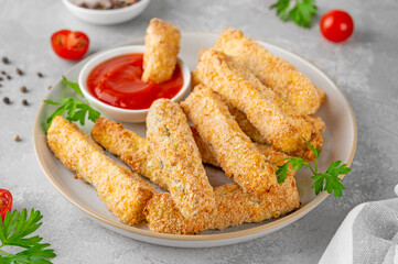 Baked crispy garlic parmesan zucchini sticks served with tomatoes sauce on a gray concrete...