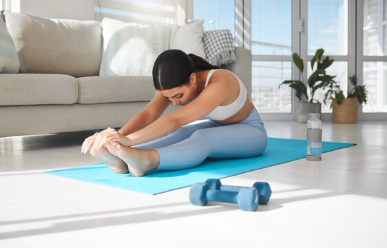 If you change nothing, nothing will change. Shot of a sporty young woman stretching while exercising at home.