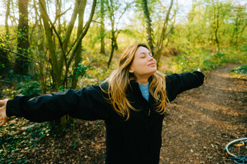 Attractive caucasian woman breathe fresh air , enjoying springtime on a sunset in natural parkland