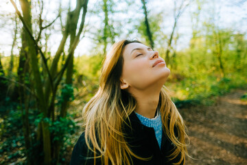 Attractive caucasian woman breathe fresh air , enjoying springtime on a sunset in natural parkland