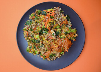 Butter chicken with grain mix and vegetables against a colorful background