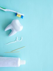 Dental concept of oral hygiene. Dental floss with plastic toothpick, big white tooth, toothpaste...