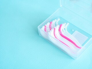 Dental floss with a plastic toothpick in white and pink color in a plastic transparent container on...