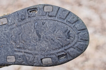 part of the boot with a rubber dirty old sole with a black pattern on a gray brown background