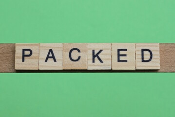 word packed made of small gray wooden letters on a green paper background
