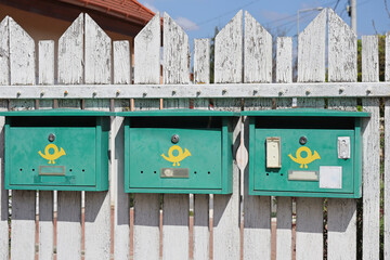 Green mailboxes on the white fence