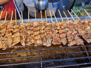 grilled beef skewers being roasted on charcoal on the steel grid to sell to customers in the night market.