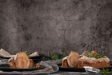 Delicious spice cake with pear, ginger and cinnamon on a dark kitchen counter.