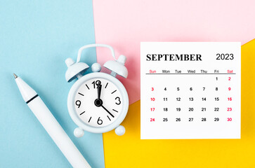 The September 2023 Monthly calendar with alarm clock and pen on beautiful background.